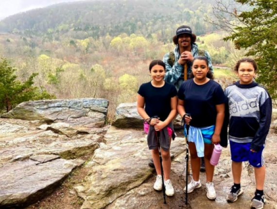 Niños caminando con un adulto sobre una roca con una vista panorámica al fondo (Instagram@kleelee19_0)