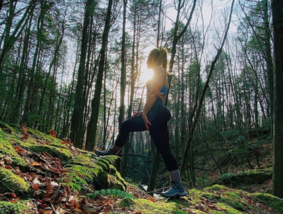 Una mujer subiendo una colina por el bosque en otoño