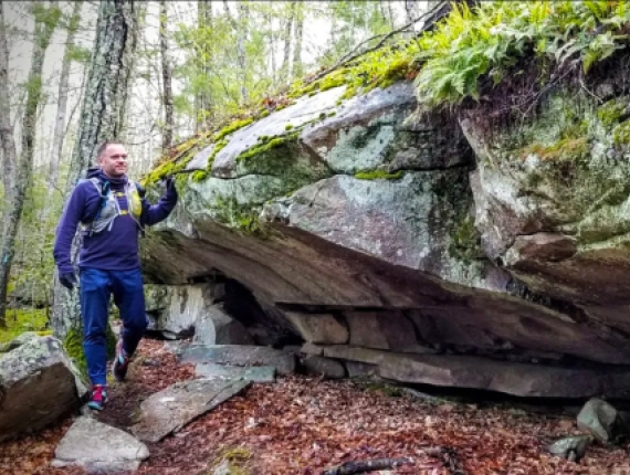 Hombre caminando a lo largo de formaciones rocosas en el Bosque Estatal Nehantic