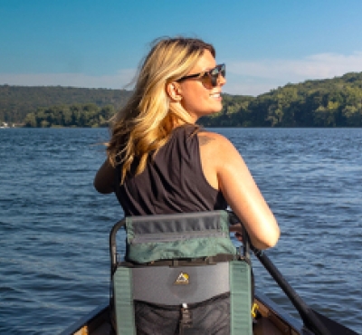 Mujer haciendo kayak y acampando a lo largo del río CT
